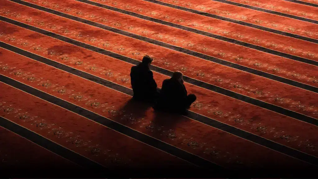 two men sitting on a red carpet